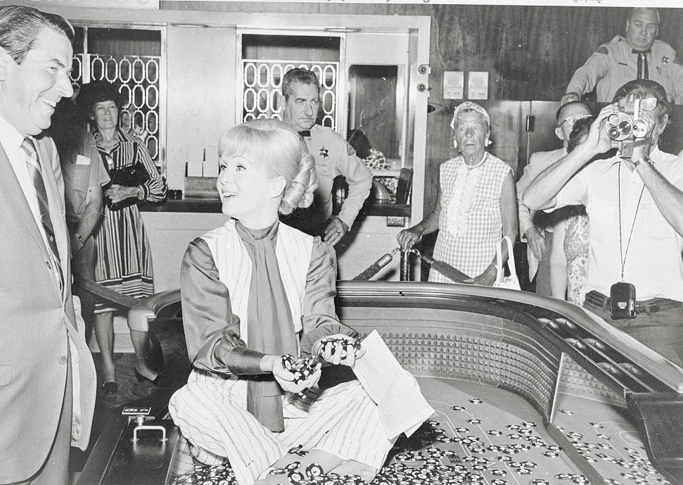 #54 Actress Debbie Reynolds, seated on a craps table in the Desert Inn in Las Vegas, 1971.