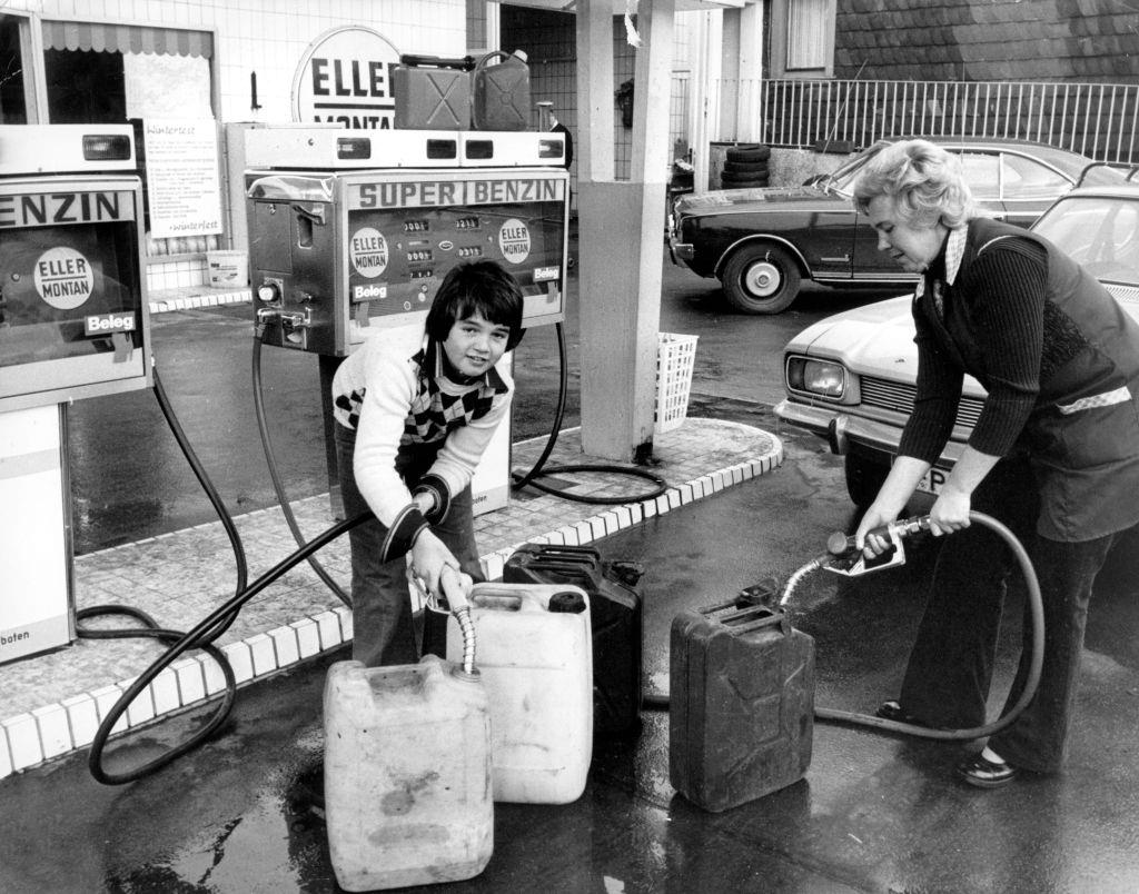 #25 A woman and a boy fill petrol canisters with petrol at a petrol station on the 7th of November in 1973.