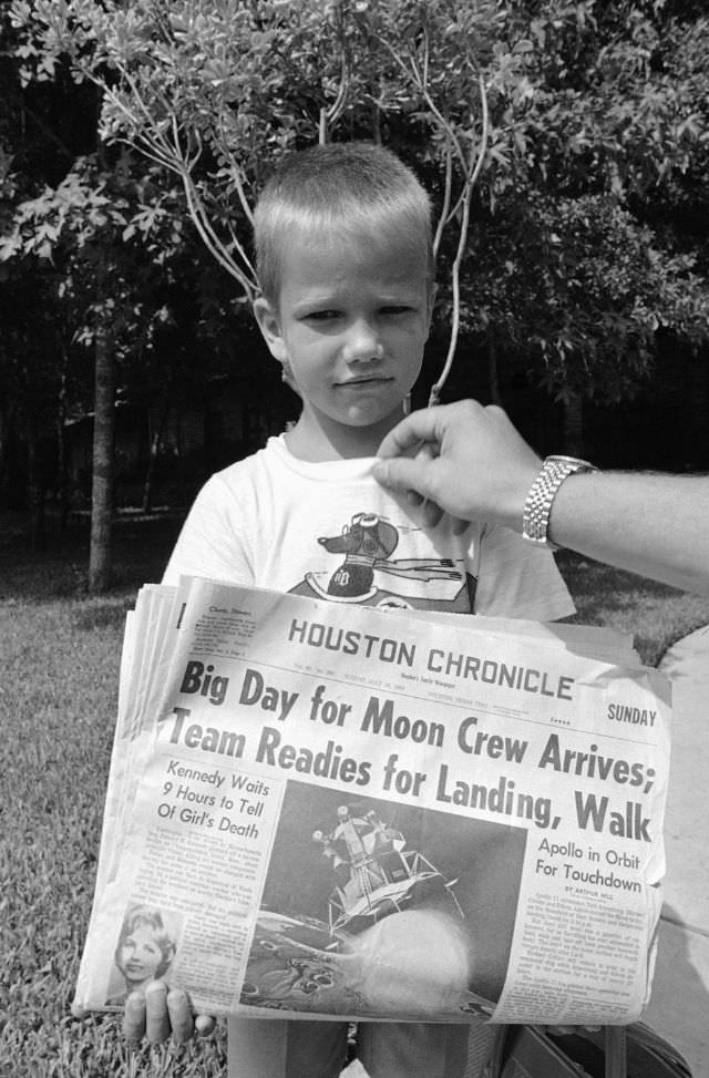 #11 Six-year-old Mark Armstrong holds the morning newspaper at the family home in Houston, Texas, on July 20, 1969.