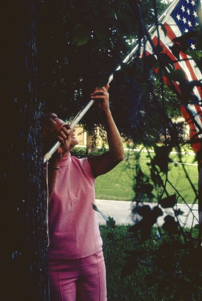 #19 A family member of Apollo XI astronaut raising a flag, Houston, Texas, July 1969