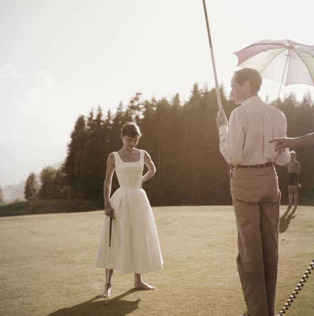 #12 Audrey Hepburn standing on the golf course at Switzerland’s Bürgenstock resort near husband Mel Ferrer, 1954.
