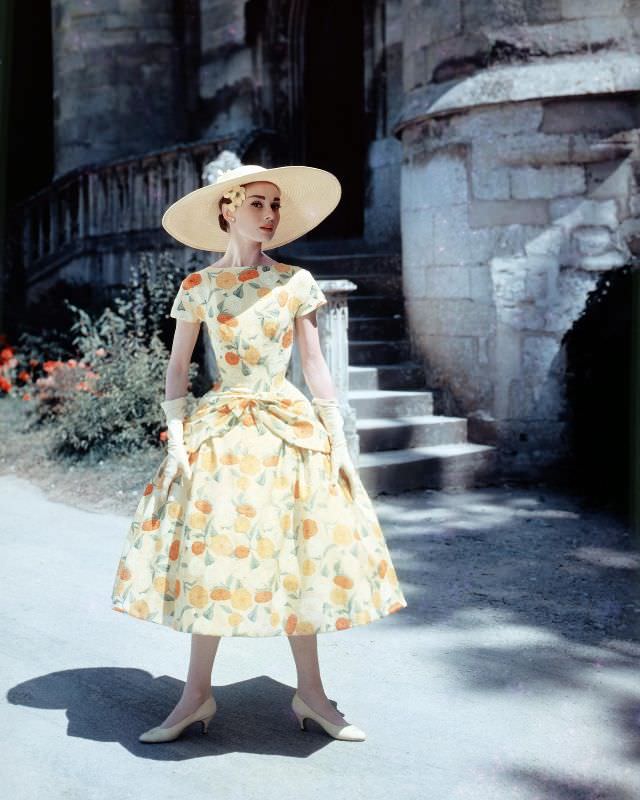 #22 Audrey Hepburn in a floral-print day dress and sun hat on the set of ‘Funny Face,’ 1957.