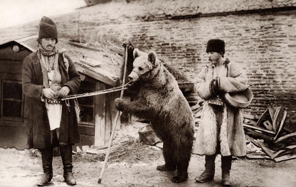 #10 Two men in native dress with a trained bear on a lead with a muzzle, Bucharest, 1910.
