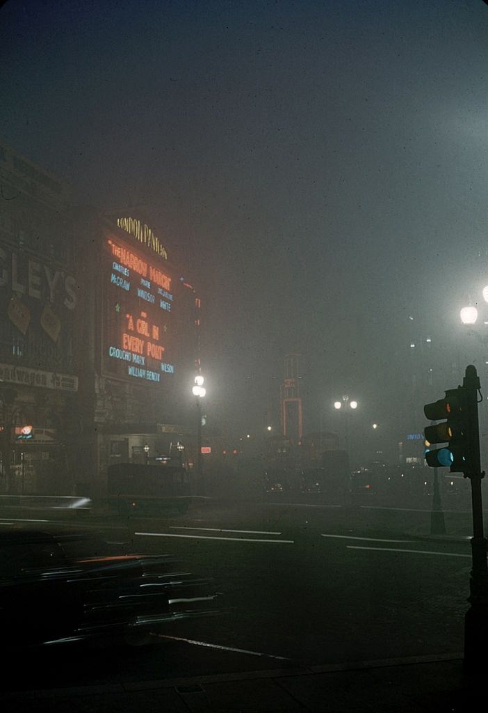 #12 View along a foggy street where pedestrians pass a parked car, London, 1952.