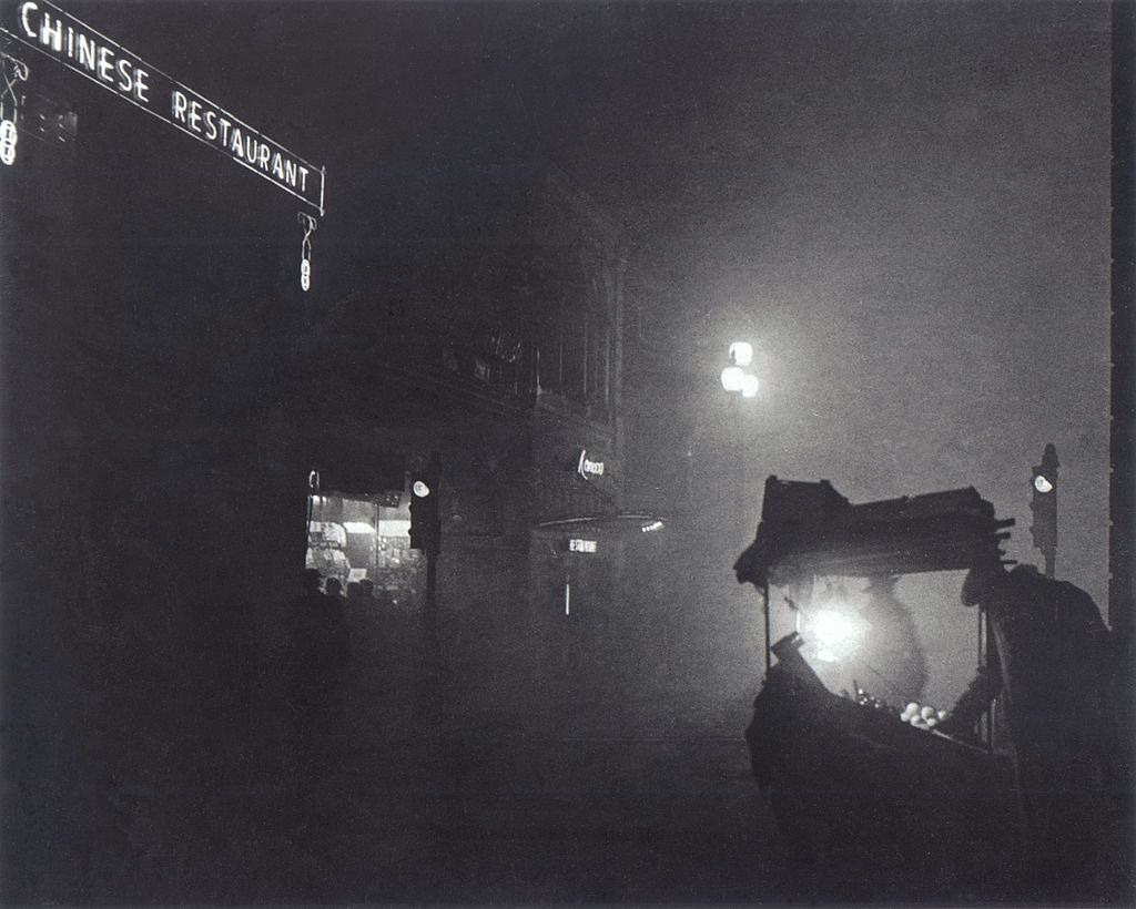 #7 A foggy Piccadilly partially lit by the light from a fruit seller’s stall, 1952.