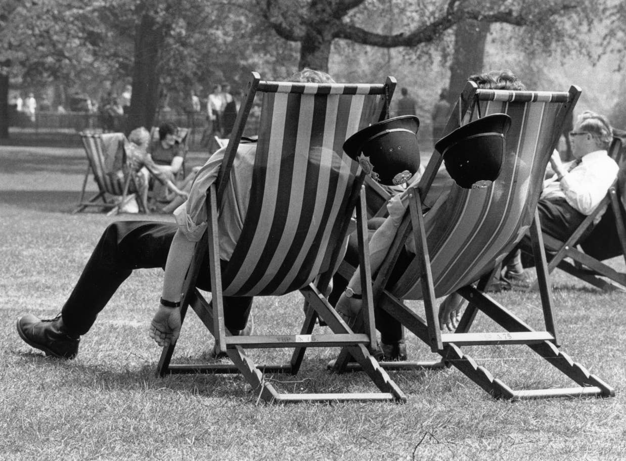 #11 Two London policemen take the weight off their feet during the heatwave, whilst patrolling the park