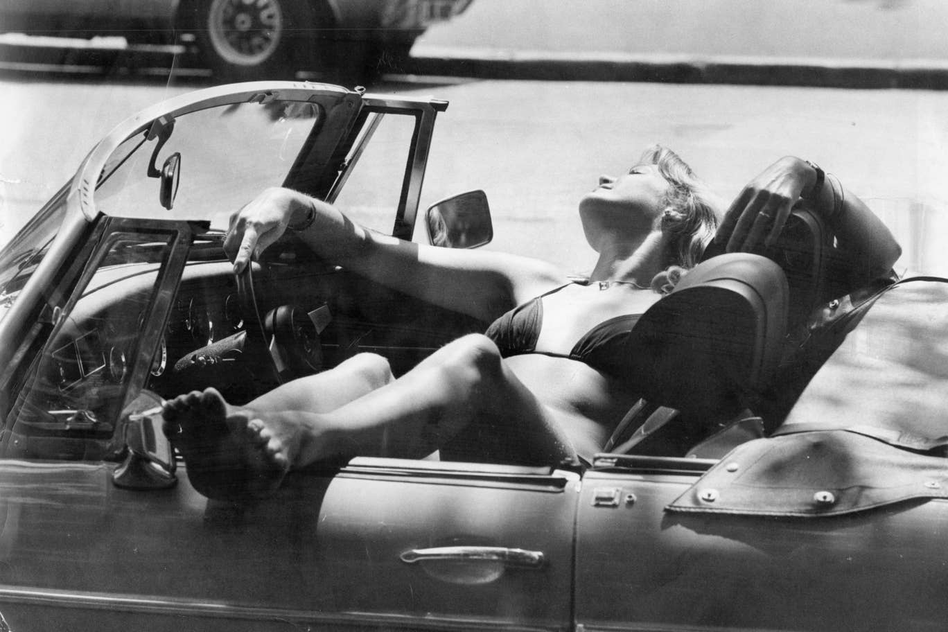 #3 A woman soaks up the sunshine in a convertible car