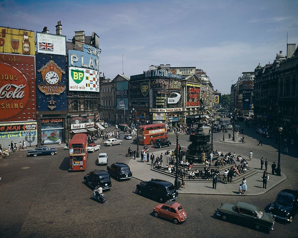 #17 View of Piccadilly Circus in London with cars and buses passing the Shaftesbury Memorial fountain and statue of Eros, 1962.