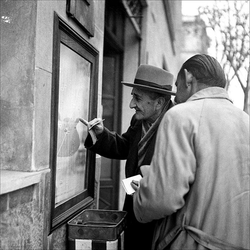 #73 Two men looking at lottery results, 1957
