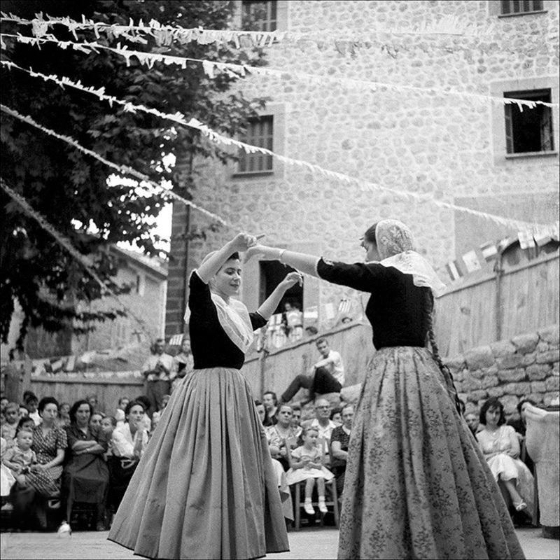 #74 Women dancing boots with people looking around in Fornalutx, 1957