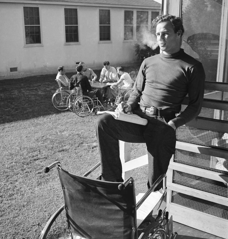 As his real-life inspirations play cards in the background, Marlon Brando takes a break from rehearsing for ‘The Men,’ Birmingham Veterans Administration Hospital, Van Nuys, Calif., 1949.