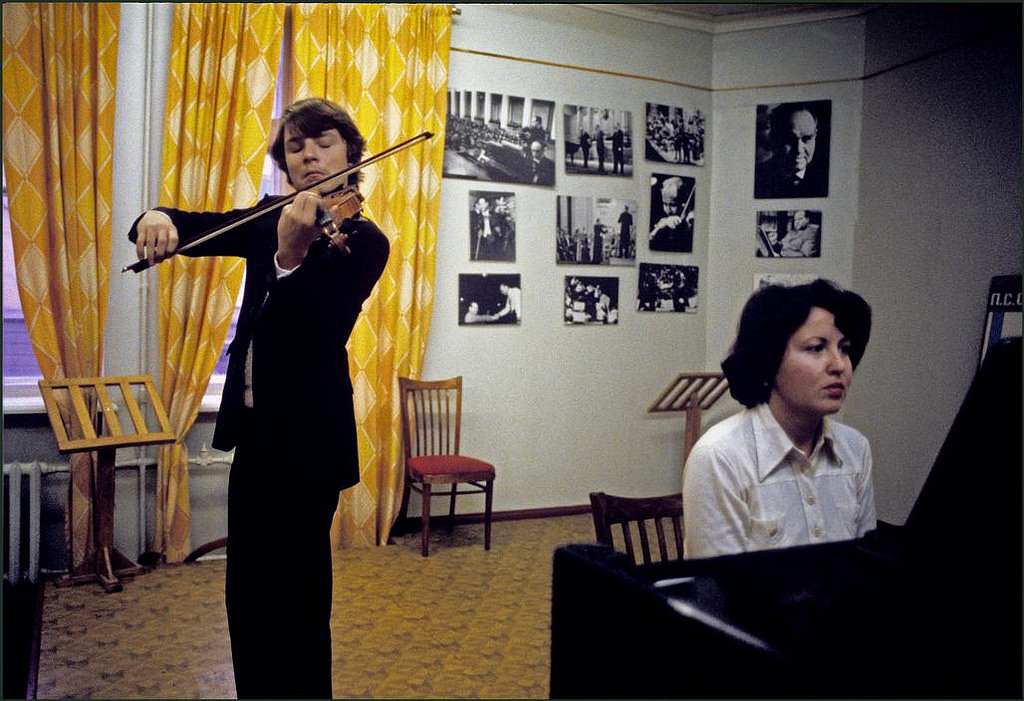 #17 One of the outstanding pupils at the famous Stolyarsky Music School playing on his violin with a piano accompaniment. Photographs of famous ex pupils on the wall.