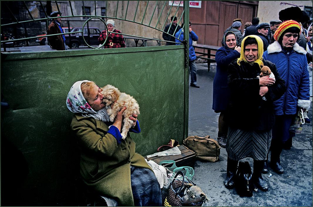 #9 A woman cuddles a dog she hopes to sell at the pet market whilst others look on.