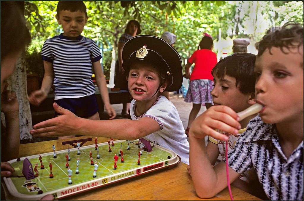 #11 Boy in toy soldiers hat playing table football whilst another sports a black eye, in the grounds of a local kindergarten.