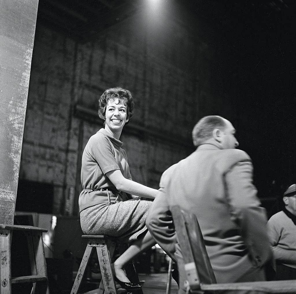 American actress and commedienne Carol Burnett sits on a stepladder backstage, along with others during the making of ‘The Twilight Zone’, 1962.
