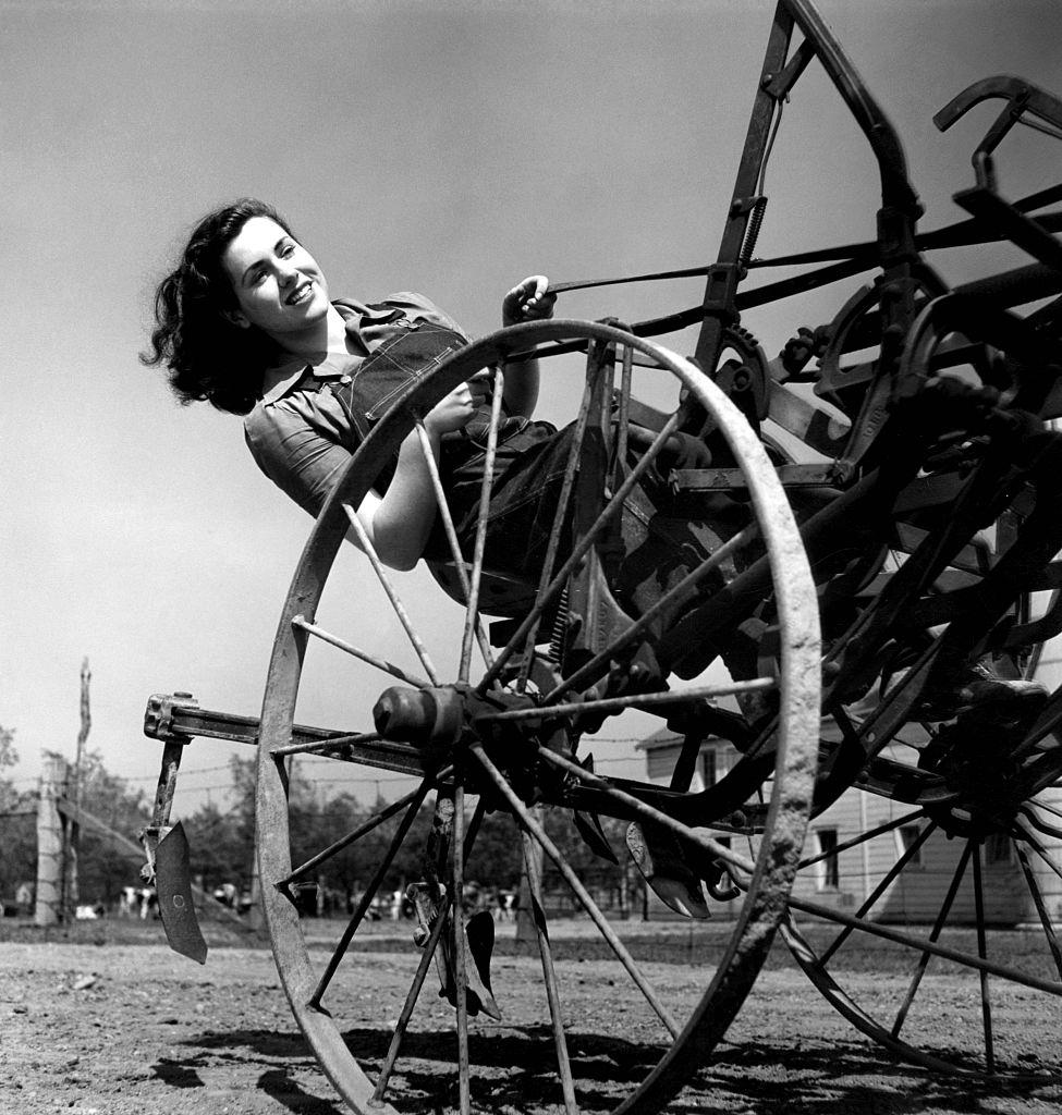 Farmer’s aide, from the Women’s Land Army, driving a cultivator over a field.