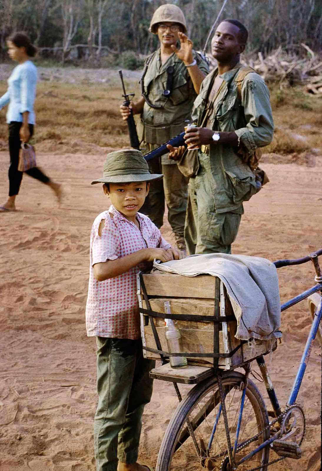 #15 Coke kid and the photographer’s platoon leader, Lieutenant Timor, with his radio telephone operator. Vietnam. February 1969.