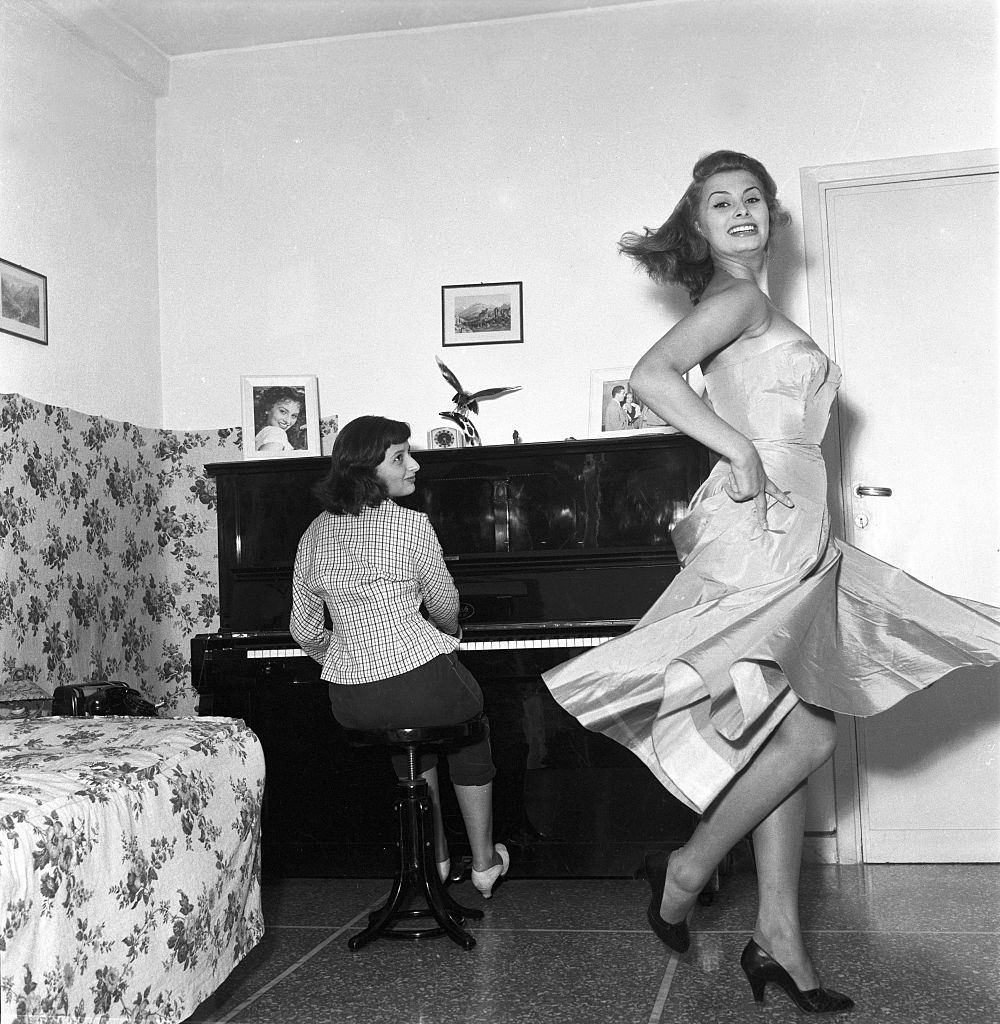 #73 Sophia Loren dacing while her sister Maria Scicolone is playing the piano, 1950s.