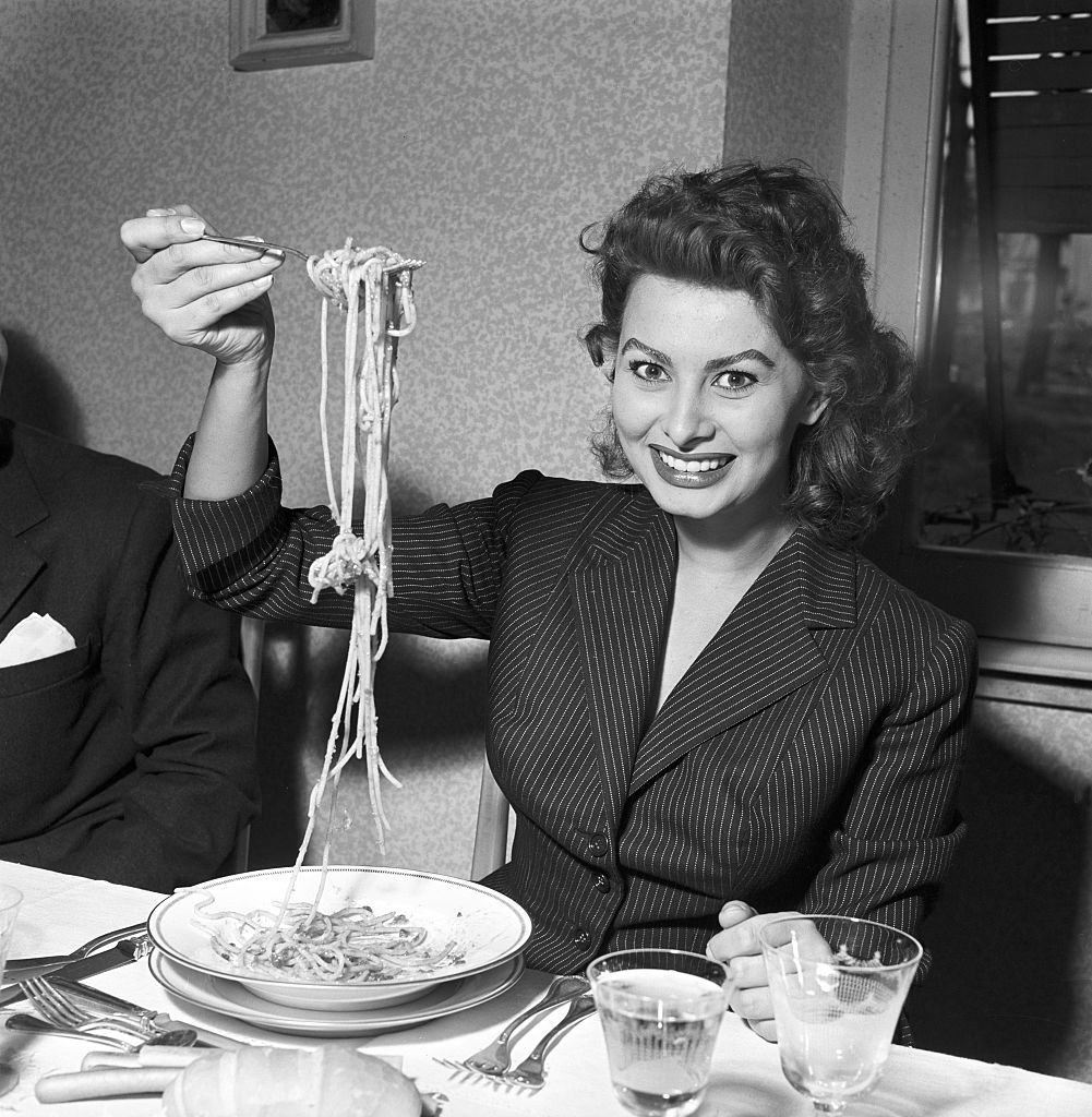 #32 Sophia Loren eating spaghetti in a restaurant, Italy, 1953.