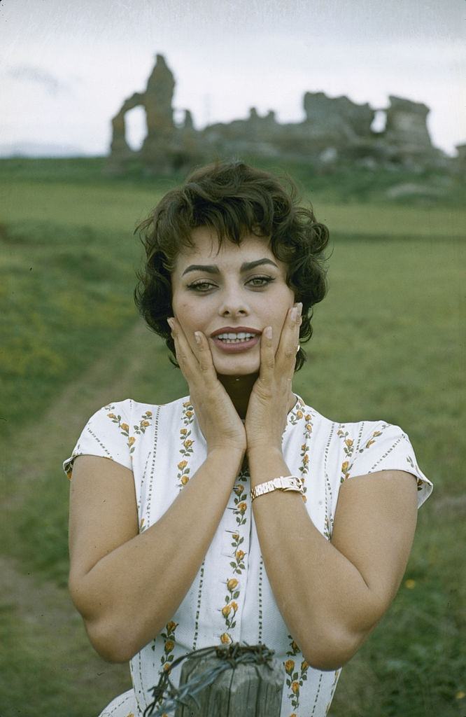 #63 Sophia Loren as she poses with her hands on her cheeks, 1957.