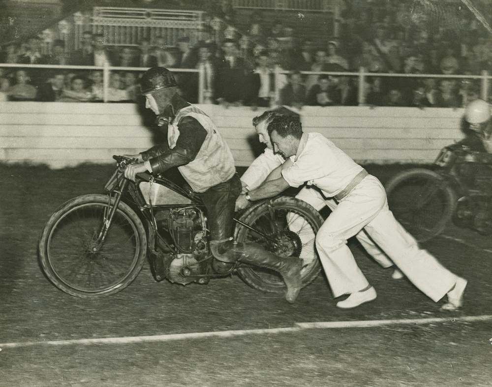 #58 Motor bike racer getting a push start at the track, Brisbane, 1955.