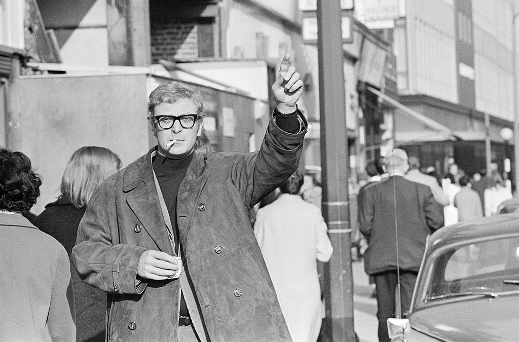 #41 Michael Caine waving towards the taxi in London, 1965.