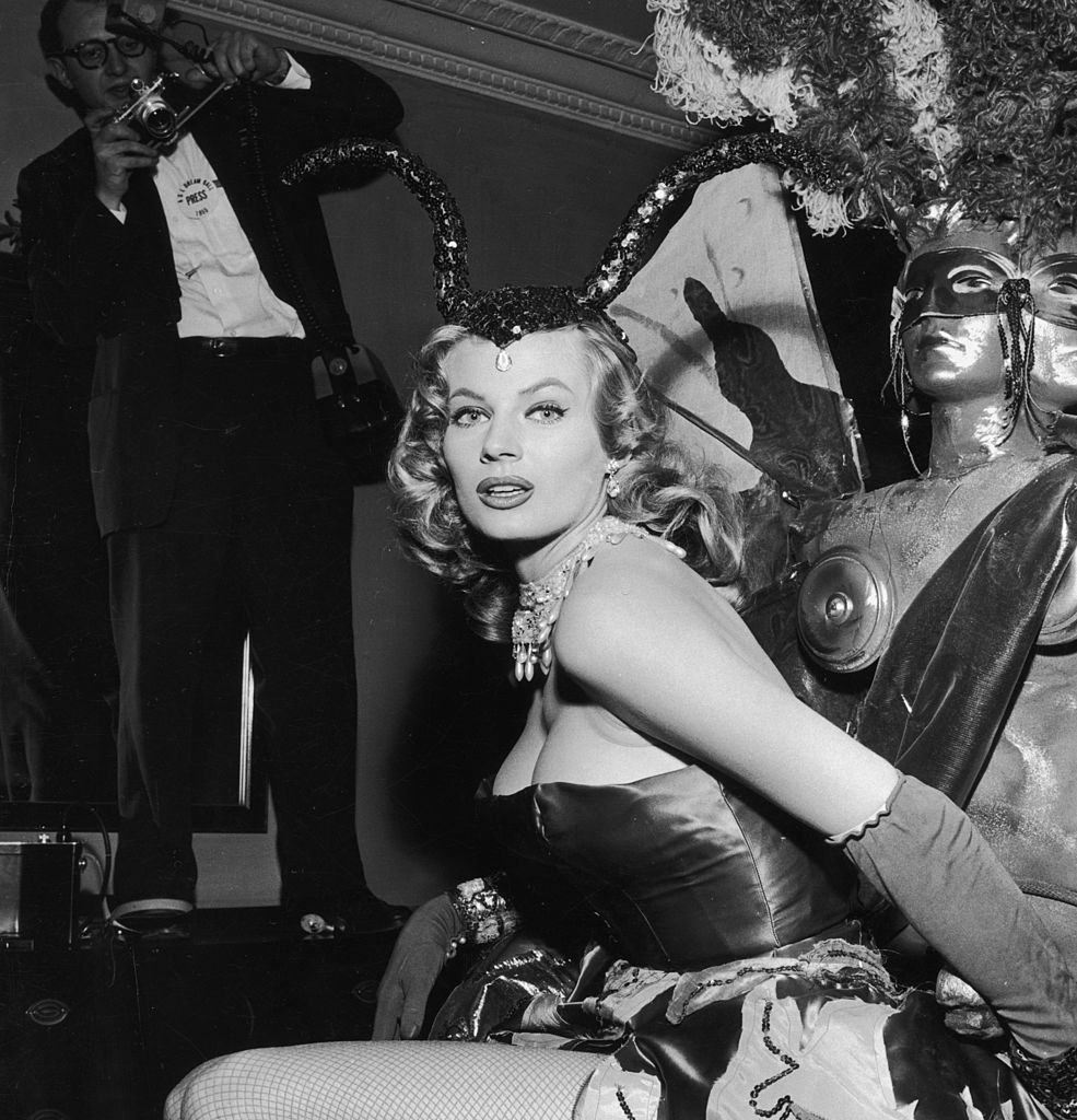 #4 Anita Ekberg poses in a strapless costume with fishnet stockings and a sequined headdress, 1955.