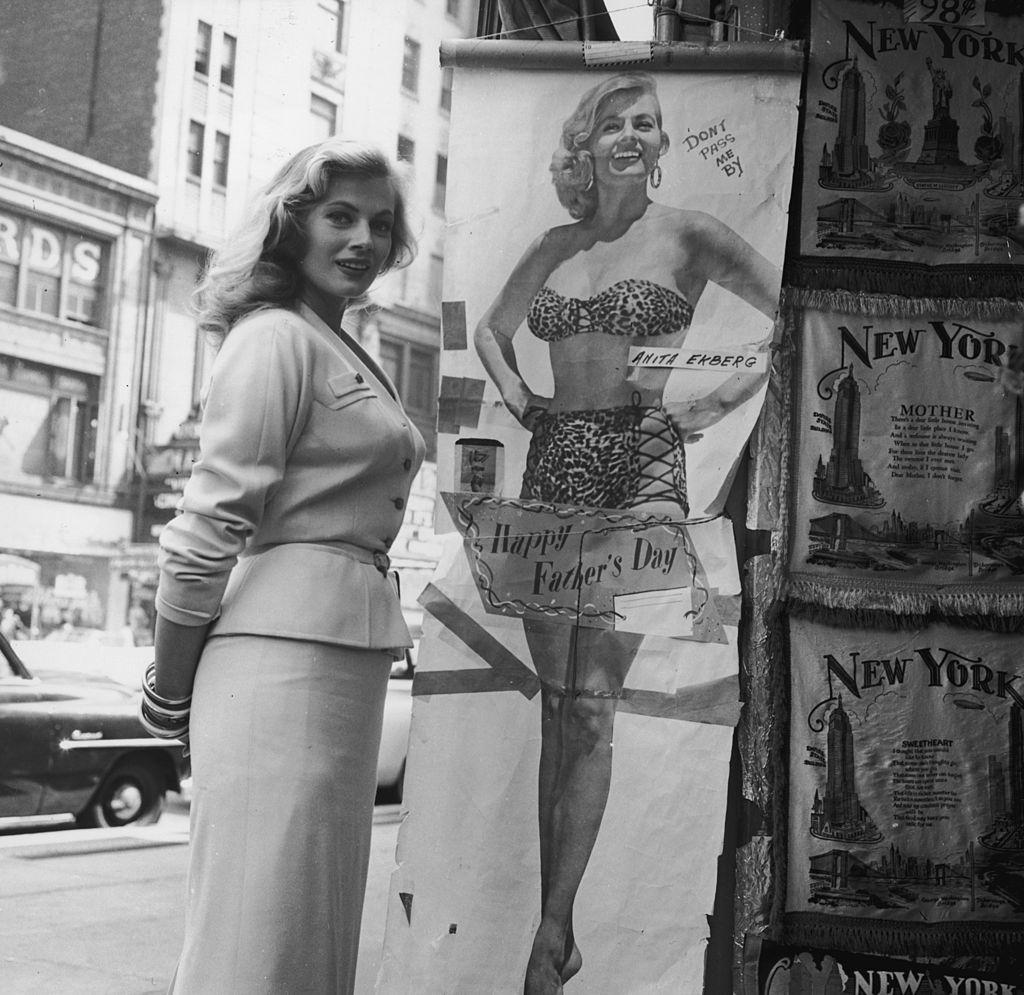#12 Anita Ekberg poses next to a full-length poster, 1958.