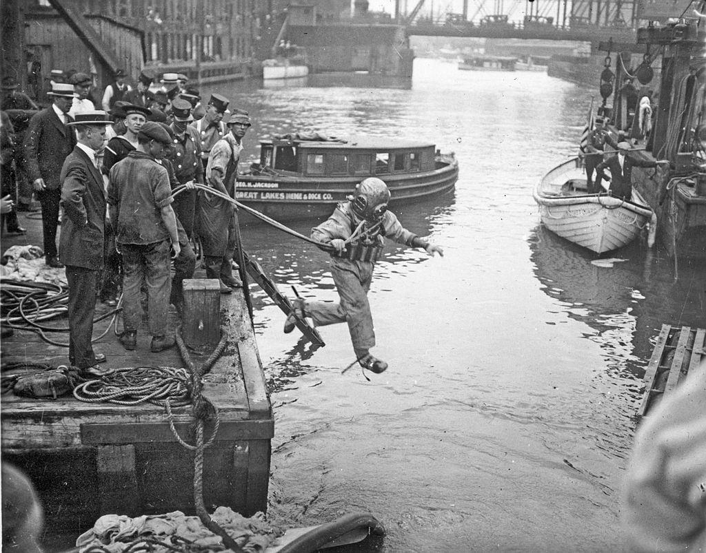 #65 A rescue worker, dressed in a diving suit, leaps into the Chicago River at the site of the Eastland disaster, July 24, 1915.