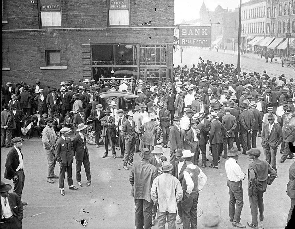 #69 Crowd in front of a storefront with the sign Bank Real Estate during the 1919 Chicago Race Riots.