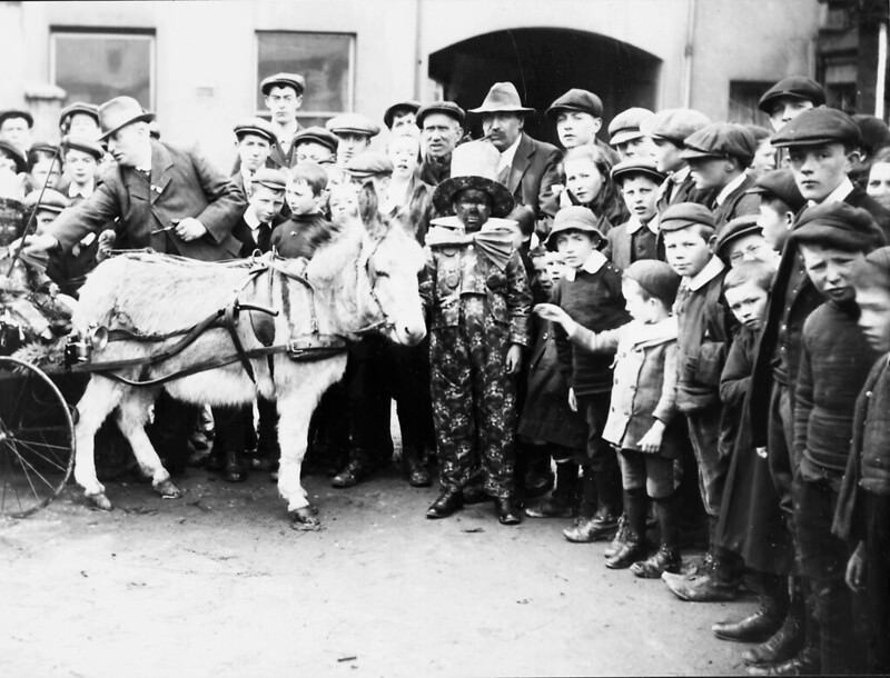 #22 A crowd of people round a clown and a donkey, 1910.