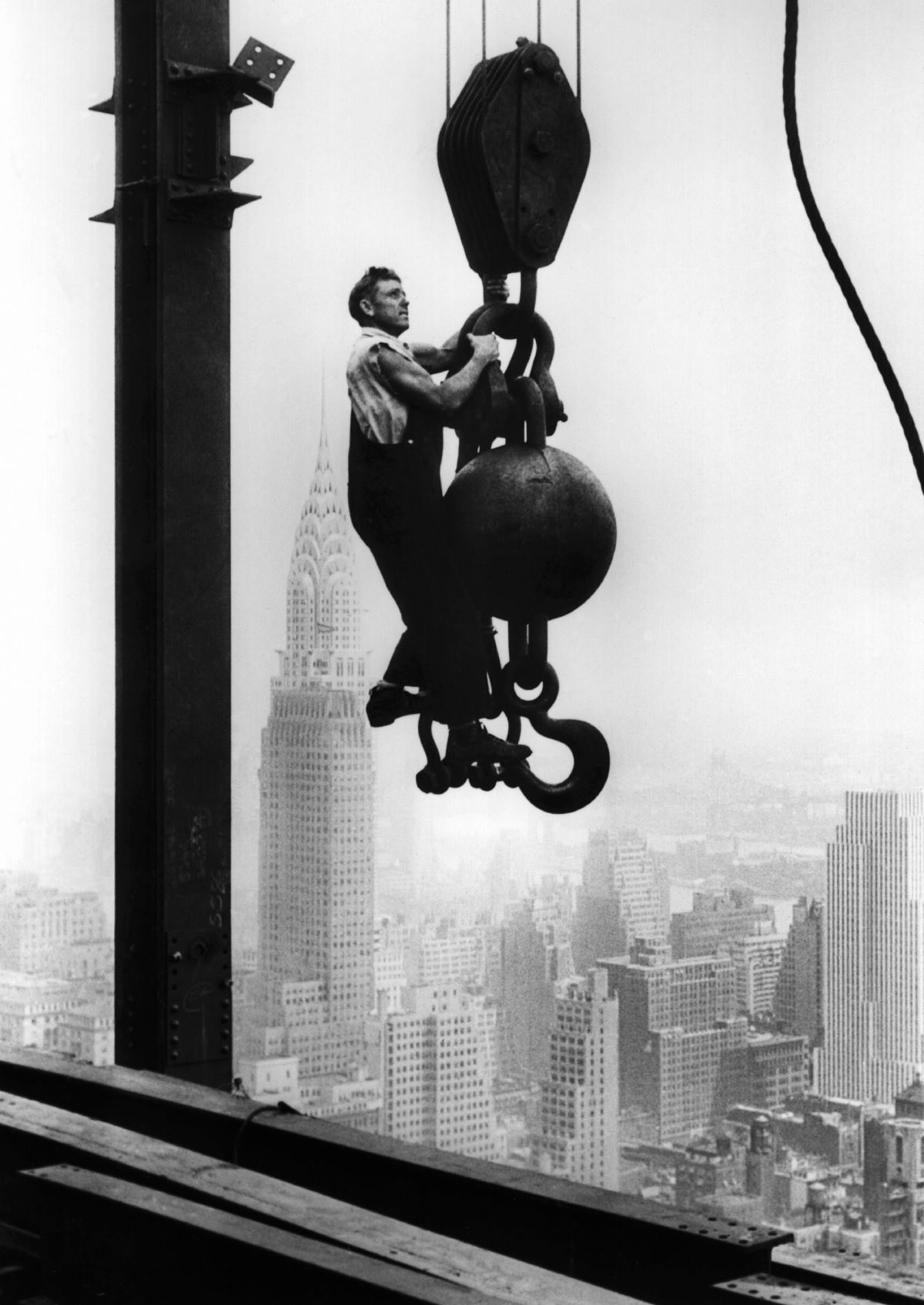 #15 A construction worker hangs from an industrial crane during the construction of the Empire State Building. Oct. 29, 1930