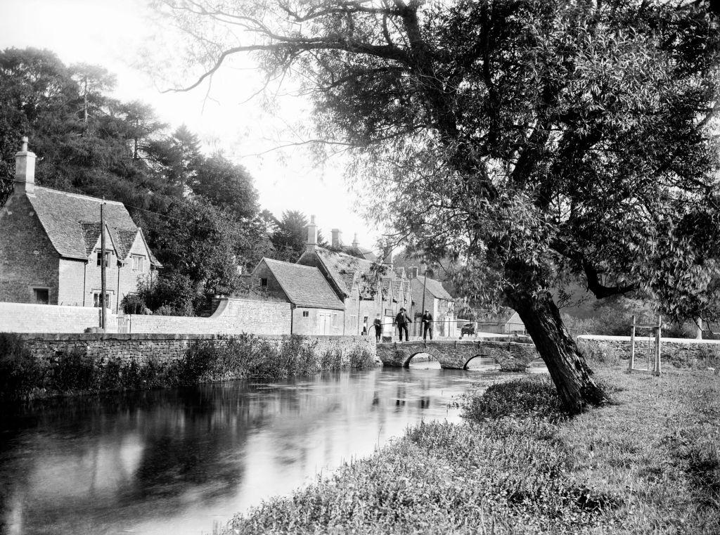 #48 Bibury, Gloucestershire, 1906. View looking along the river towards the stone bridge beside Arlington Row.