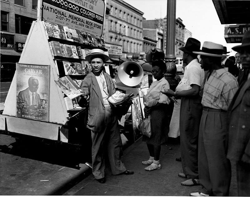 #22 A vendor showing his wares at a bookstall on 125th Street, 1943.