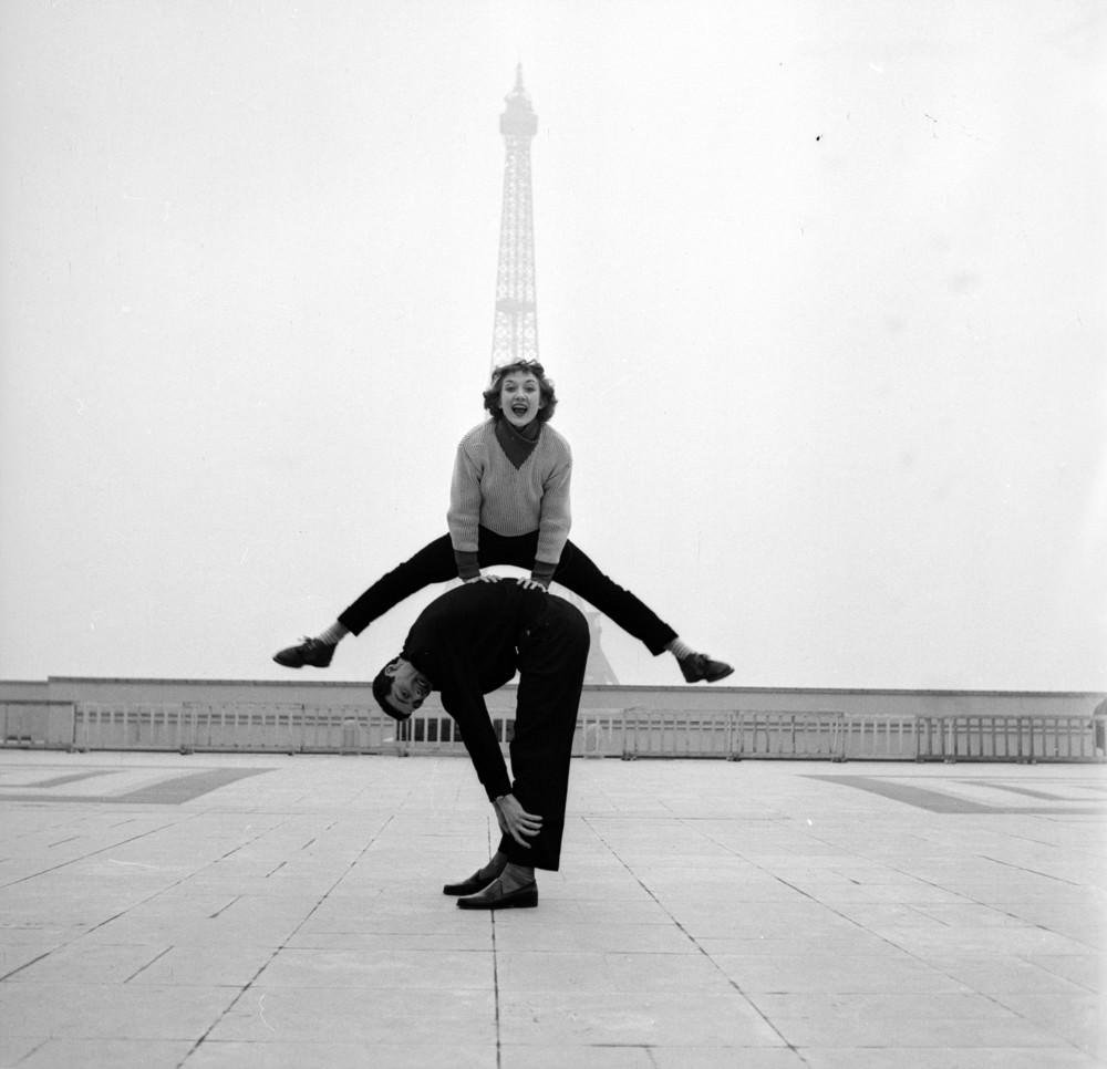 #25 Paris street performers Jean Louis Bert and Grethe Bulow playing leap-frog in front of the Eiffel Tower, 1955.
