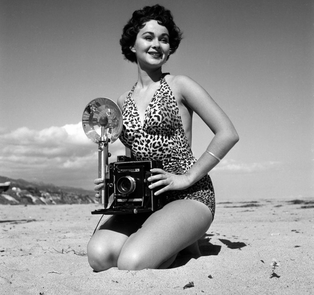 #23 Marla English holding a camera at Los Angeles beach, 1954.