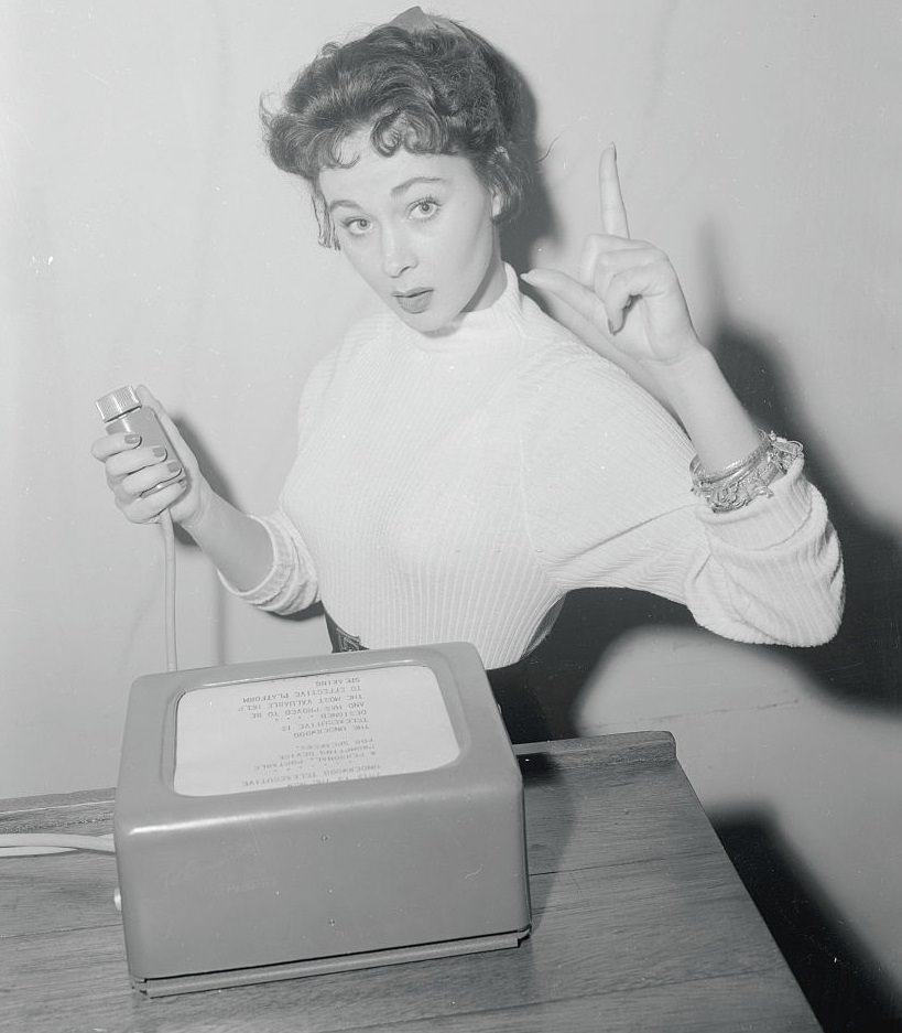 #32 Marla English supplies the gestures as she reads a speech from a machine, 1955.