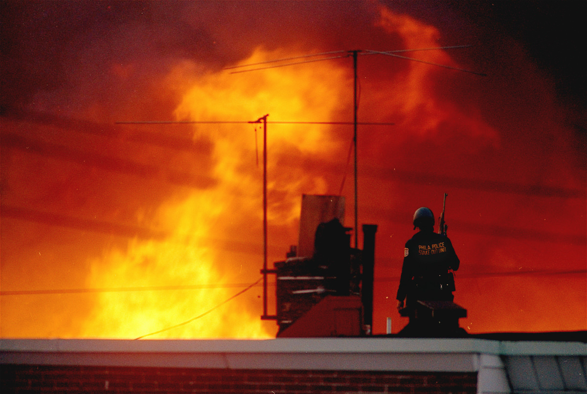 #1 A Philadelphia police officer watches a block of houses burn. May 13, 1985