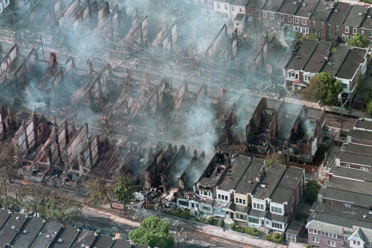 #13 Dozens of houses continue to smolder the day after the bombing. May 14, 1985