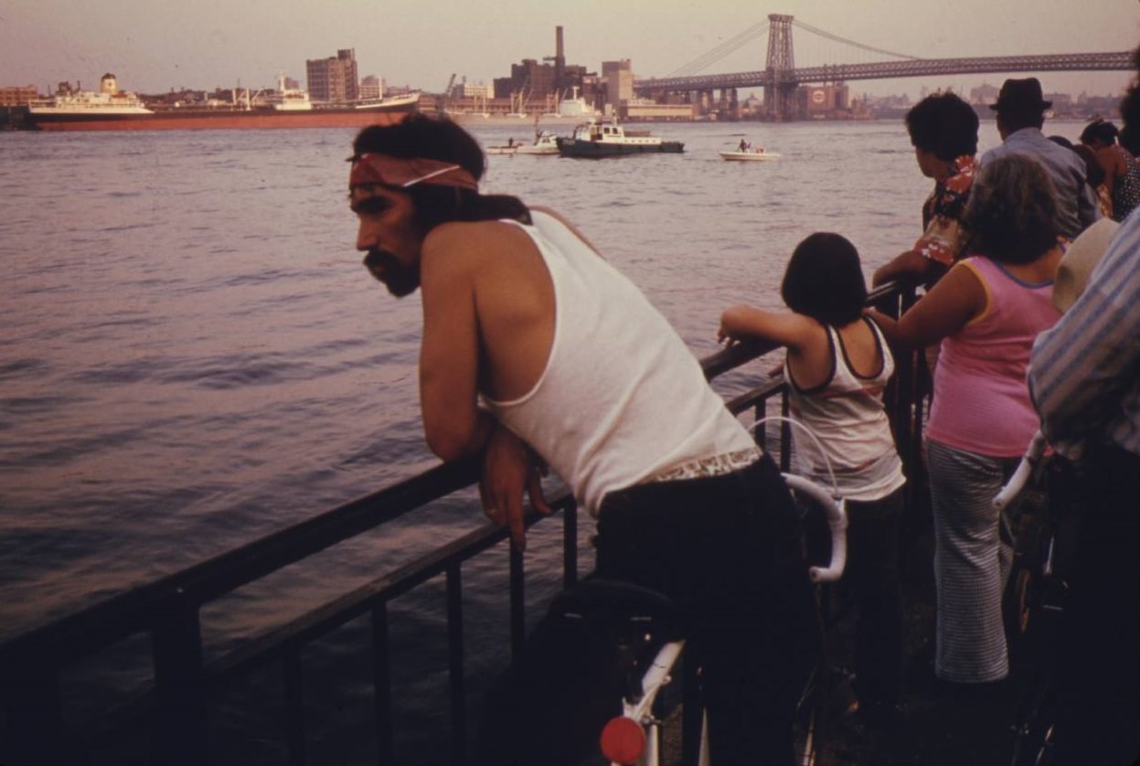 #10 People looking at boat traffic on the East River with the Manhattan Bridge and NYC in the background, July 1974.