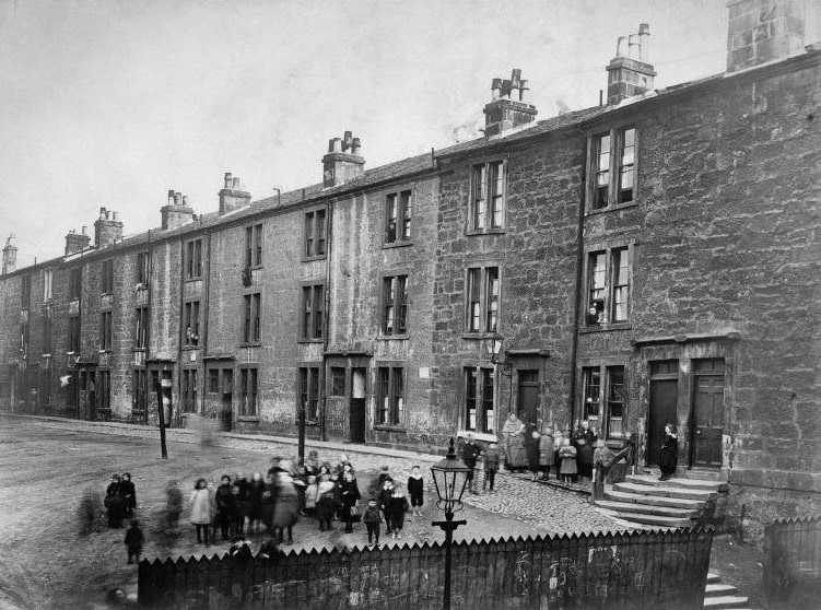 #16 St. James Terrace, Glasgow, with large group of children outside, c.1910. Titled below: ‘ 3 dwellings, 3 apartments, 24 dwellings, 1 apartment: 2 wash-houses containing in all 29 taps and 8 W.Cs