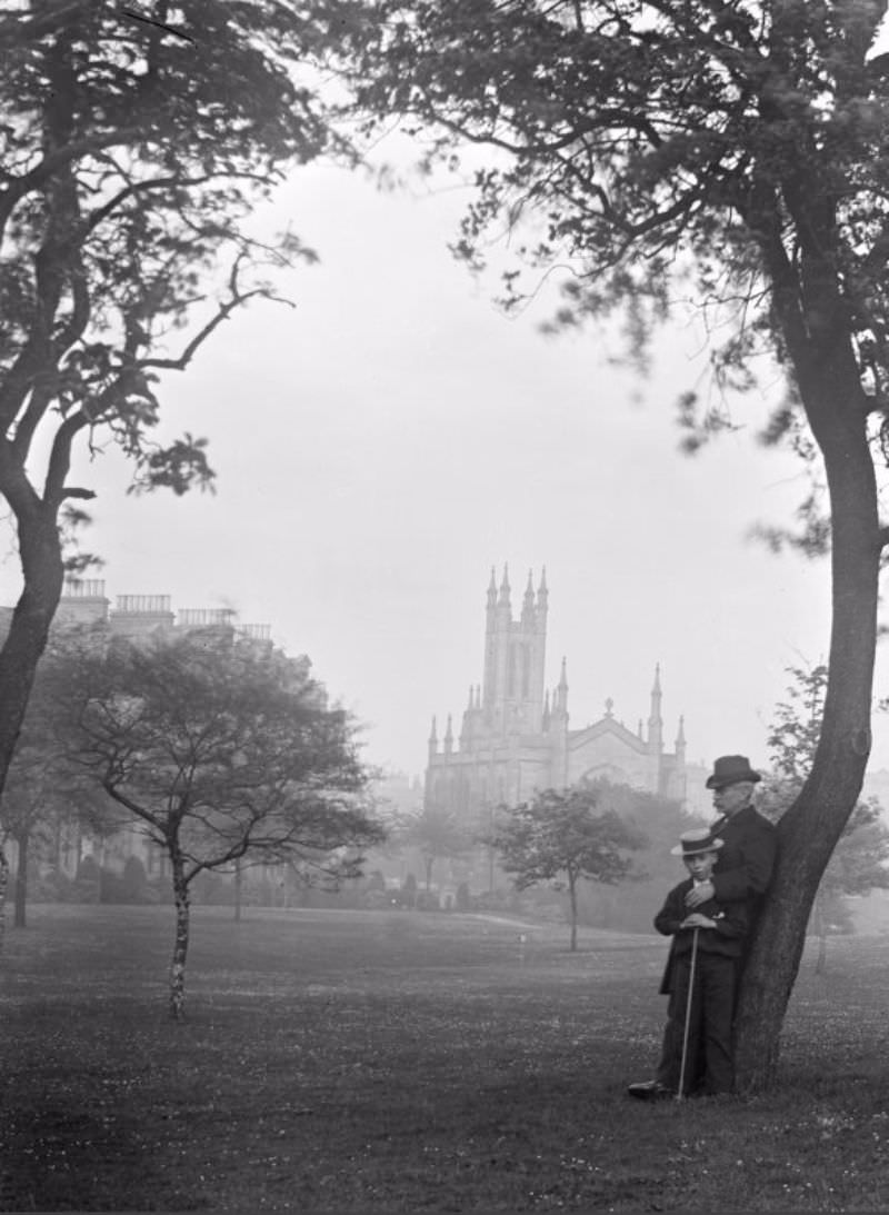 #17 Gentleman and boy leaning on tree with a distant view of Holy Trinity Church, c.1900.