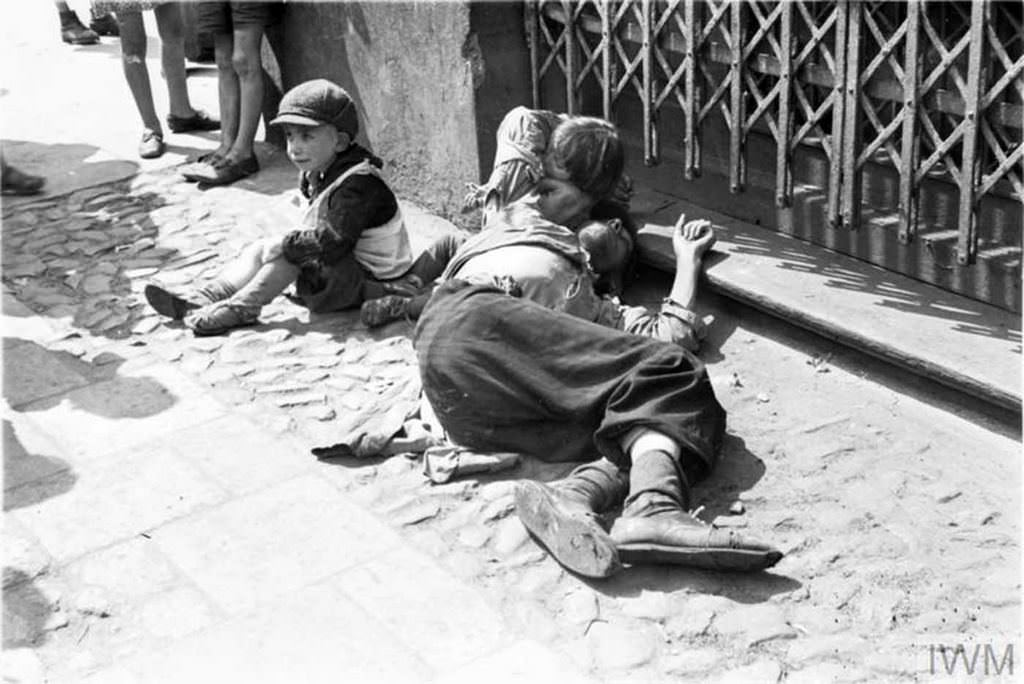 #15 A starving man (father ?) and two emaciated children begging on the street in the ghetto.