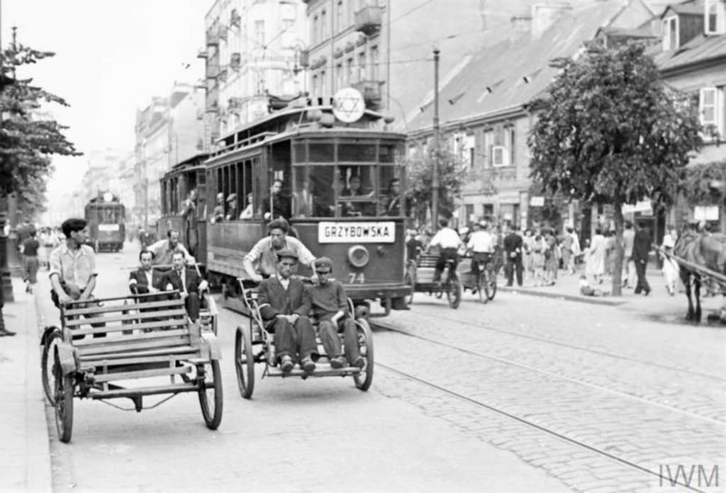 #25 Street rickshaws and a tramcar carrying passengers along Leszno Street in the ghetto, summer 1941. This particular tramline was run between the Muranowski Square and the Grzybowska Street. The plaque on the tram indicates it runs towards Grzybowska Street.