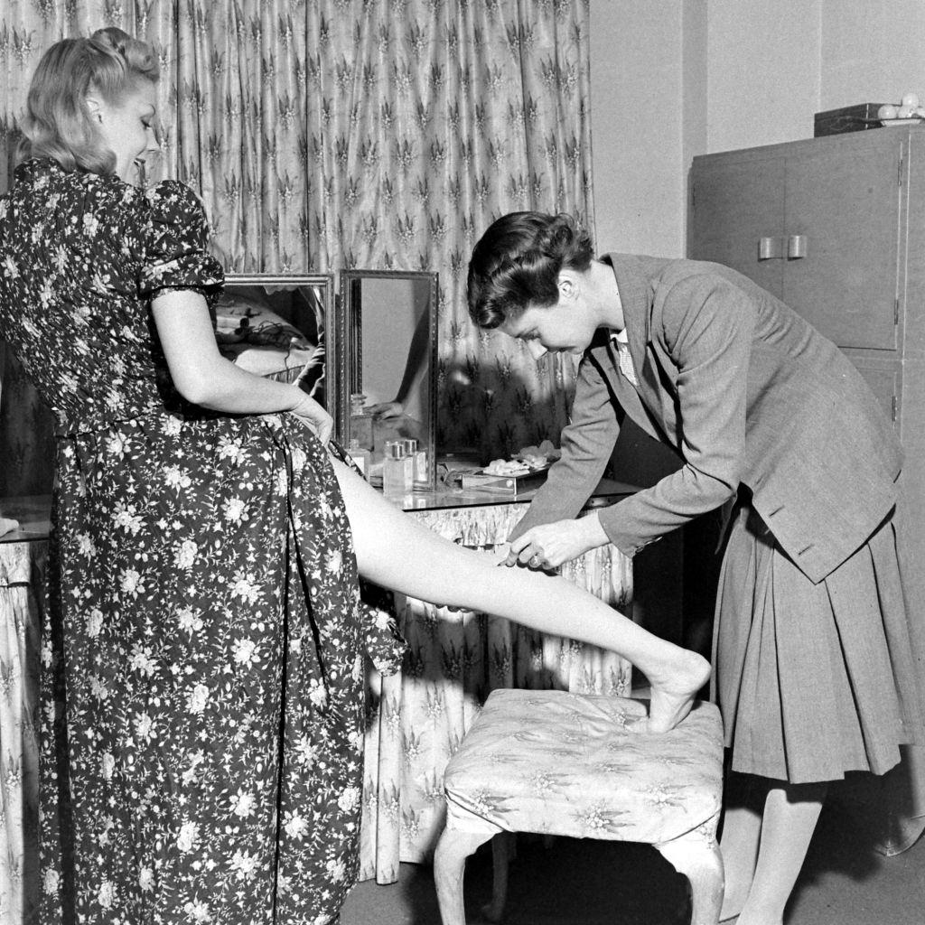 #12 A woman helping another woman with the liquid stockings during WWII