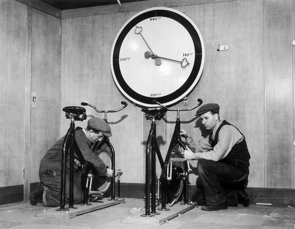 #15 At the time of the installation of the English liner Queen Mary, workmen in the gymnasium of the ship are setting up exercise bikes, with an enormous meter indicating the distance covered. 1932