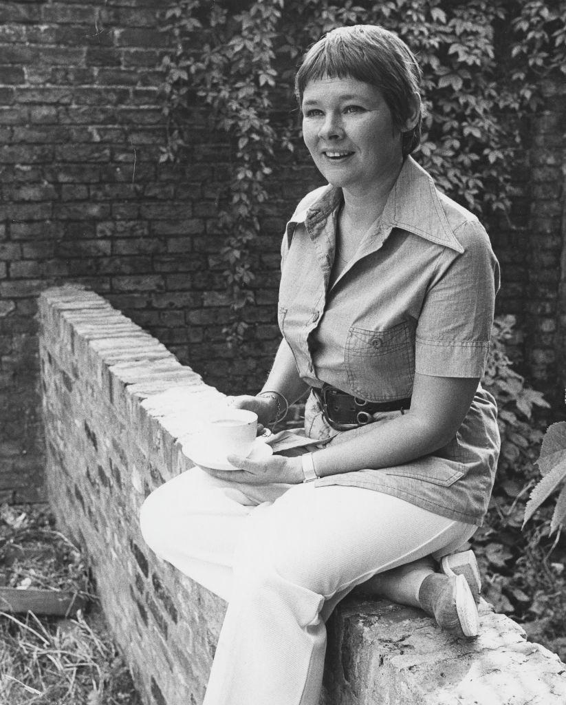 #29 Judi Dench sitting on a brick wall outside her home in Hampstead, 1973.