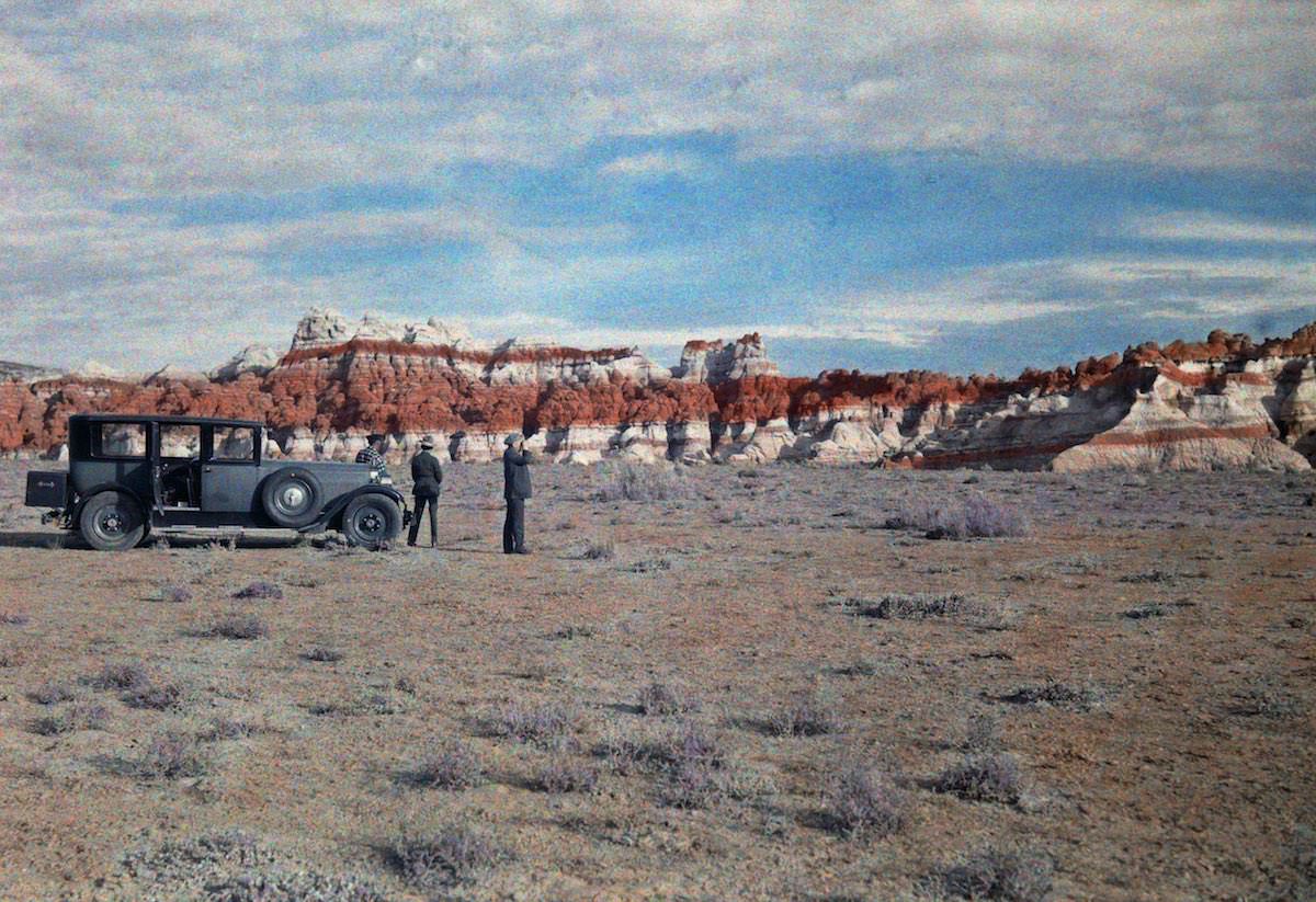 #37 Men stand next to a car in a field and look at a nearby canyon. Hopi Indian Reservation