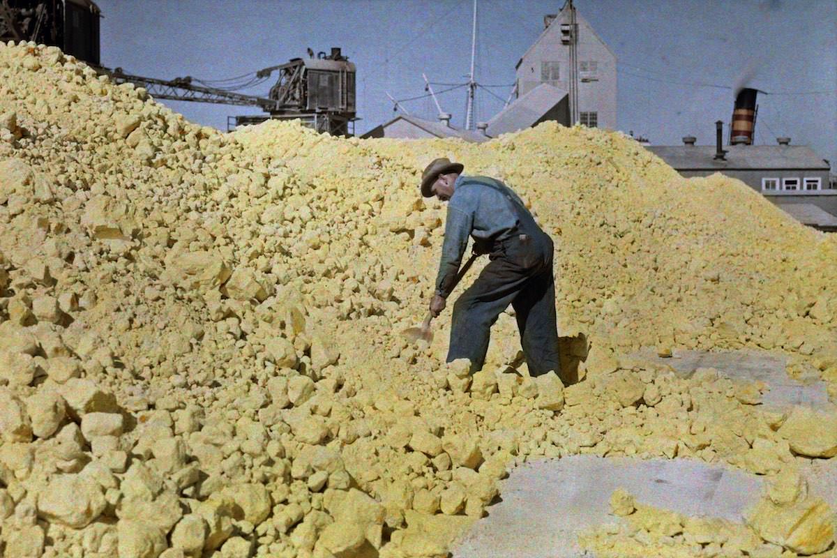 #46 A man shovels sulfur in a warehouse near the pier, Galveston, Texas.