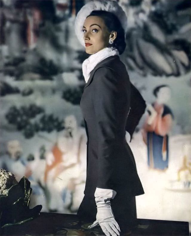 #14 Model in all-day suit of gray Miron worsted broadcloth with longer jacket by Larry Aldrich, dressed up with ermine ascot and beret, 1947